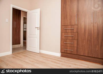 Bedroom of New House with build in cupboards, and laminated floor, as viewed towards the open door to the bedroom.