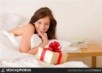 Bedroom surprise present - young happy woman in bedroom