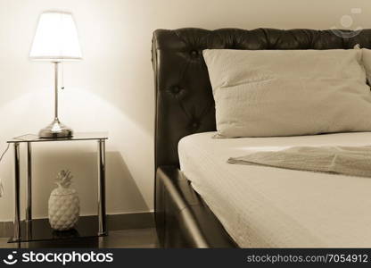 bedroom with double bed and table lamp, sepia toning
