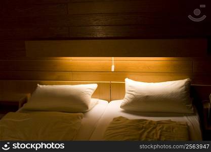 bedroom with two white pillows and light falling on top of bed