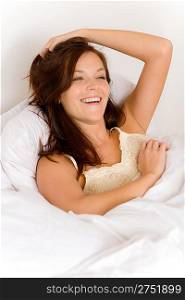 Bedroom - woman waking up and stretching in white bed