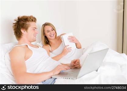 Bedroom - young couple with laptop and book in white bed