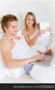 Bedroom - young couple with laptop and book in white bed