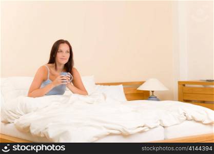 Bedroom - young woman drink coffee lying in white bed