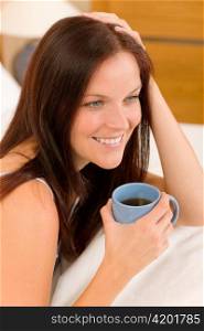 Bedroom - young woman drink coffee lying in white bed