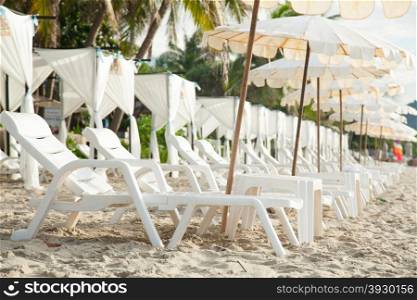 Beds and umbrellas lined up on the beach by the sea. Sleeping in tourism
