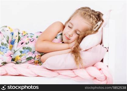 Bedtime. Little girl is sleeping in the bed. Soft bed with pink linen in white bedroom. Child sleep regime hours, daily routine. Sweet dreams concept. Bedtime. Little girl is sleeping in the bed. Soft bed with pink linen in white bedroom. Child sleep regime hours, daily routine. Sweet dreams concept.