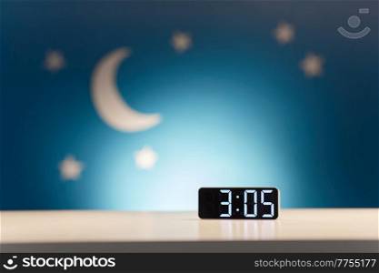 bedtime, sleeping and time concept - close up of alarm clock showing 3 am on table over moon and night stars on blue background. alarm clock on table over night background