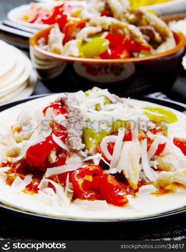 Beef and chicken Fajitas with colorful bell peppers in tortilla bread and sauces