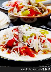 Beef and chicken Fajitas with colorful bell peppers in tortilla bread and sauces
