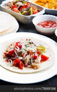 Beef and chicken Fajitas with colorful bell peppers in tortilla bread and sauces