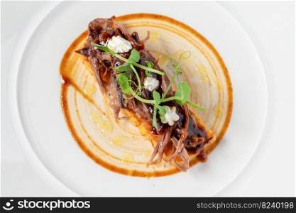Beef bruschetta on a white porcelain plate on a dark gray table