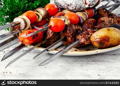 Beef cooked with vegetables on skewers and baked potatoes. Meat roasted on skewers