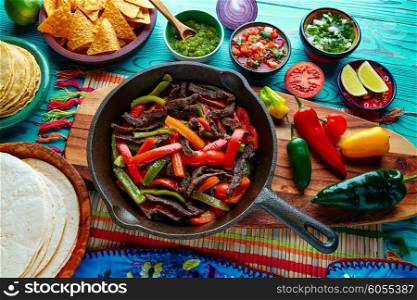 Beef fajitas in a pan with sauces chili and sides Mexican food