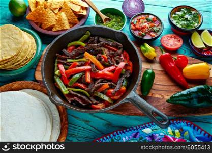 Beef fajitas in a pan with sauces chili and sides Mexican food