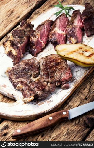 beef grilled steak. Grilled steak sliced in pear sauce on cutting board