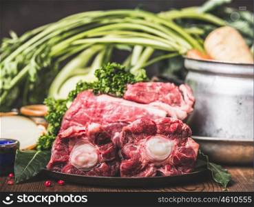 Beef Ox tail meat on kitchen table with cooking pot and vegetables ingredient, side view, close up