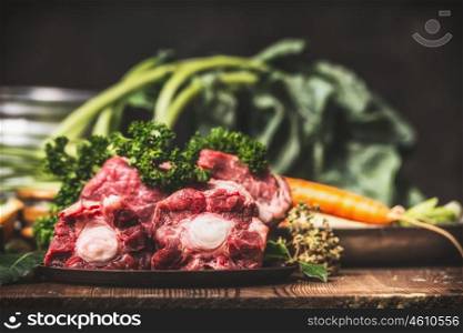 Beef Ox tail meat with bone and cooking ingredients for soup or broth on rustic kitchen table