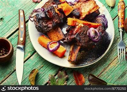 Beef ribs BBQ on wooden table.Baked beef meat with slices of pumpkin. Grilled meat with pumpkin,top view