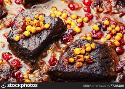 Beef roasted in autumn berries. Meat with cranberries and sea buckthorn.Close up. Delicious fried beef with berry gravy