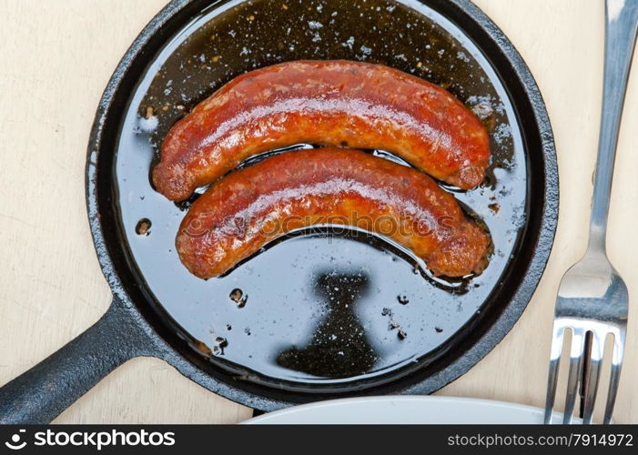 beef sausages cooked on iron skillet with carrot and onion