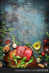 Beef steak and various ingredients for cooking on rustic wooden background, top view, frame. Healthy, diet food concept.
