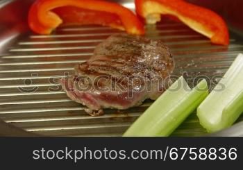 Beef steak grilled with vegetables in a frying pan
