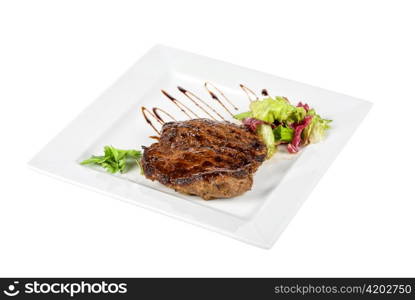 Beef steak on a white plate with vegetables on a white