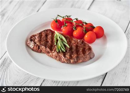 Beef steak with cherry tomatoes and fresh rosemary on white plate