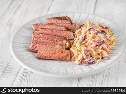 Beef steak with coleslaw salad on wooden table
