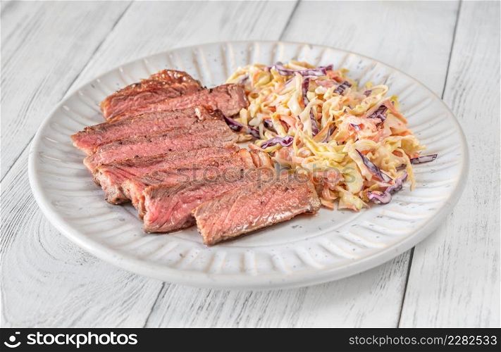 Beef steak with coleslaw salad on wooden table