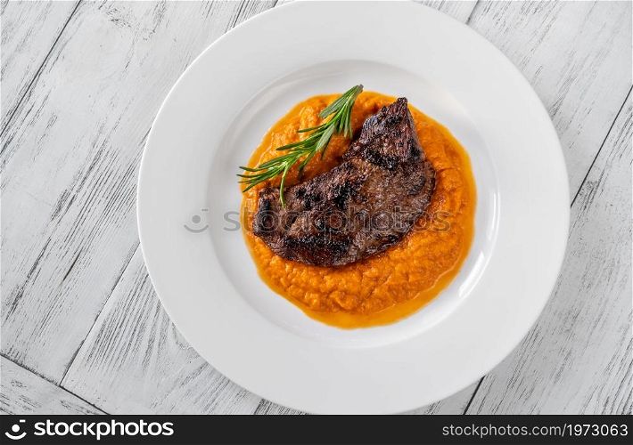 Beef steak with mashed pumpkin on white plate