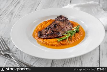 Beef steak with mashed pumpkin on white plate