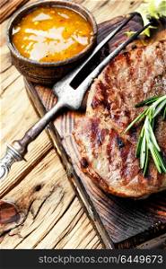 Beef steak with twig rosemary. Grilled beef steak on cutting board and sauce.Beef meat