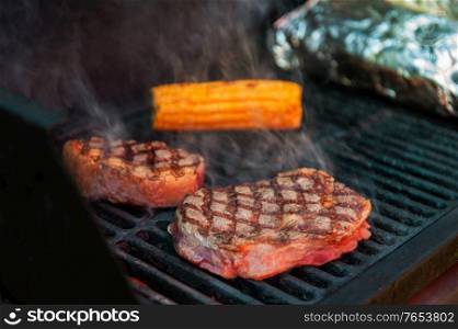 Beef steaks with vegetables on the grill with flames. Beef steaks on the grill with flames