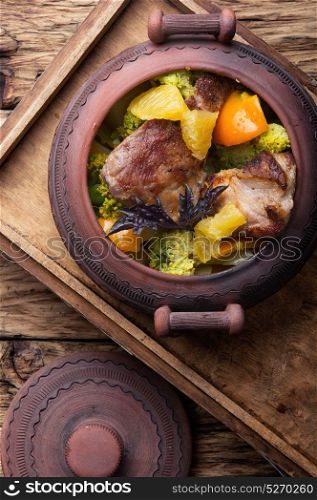 Beef stew in ceramic pot. baked meat with orange sauce in a rustic ceramic pot