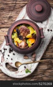 Beef stew in the pot. baked meat with orange sauce in a rustic pot