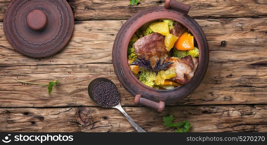 Beef stew in the pot. baked meat with orange sauce in a rustic pot