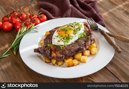Beefsteak with fried egg and potato close up