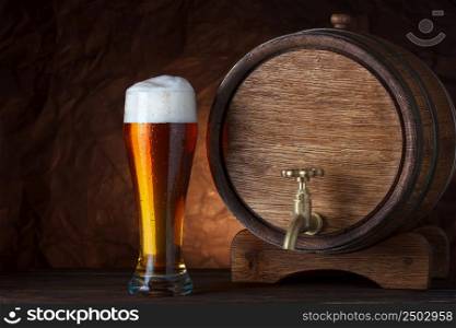 Beer barrel with beer glass on wooden table dark still-life