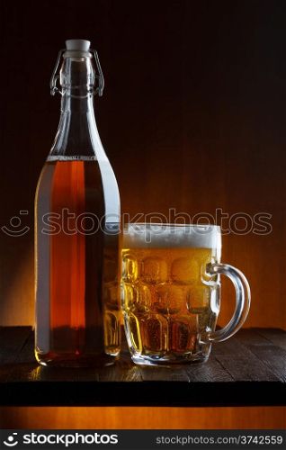 Beer bottle and mug on wooden table still life