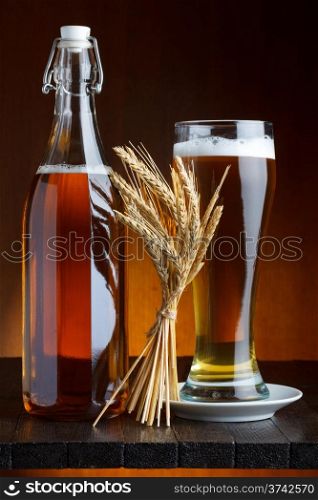 Beer bottle and mug with wheat on wooden table still life