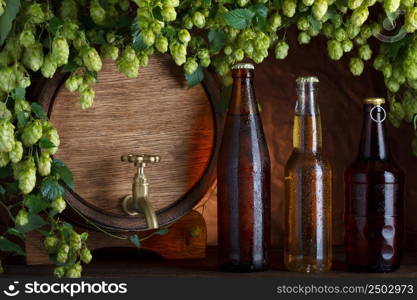 Beer bottles with beer barrel and fresh hops frame still-life