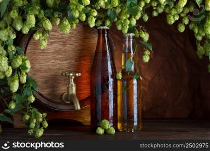 Beer bottles with beer barrel and fresh hops frame still-life