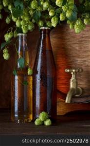 Beer bottles with beer barrel and fresh hops still-life