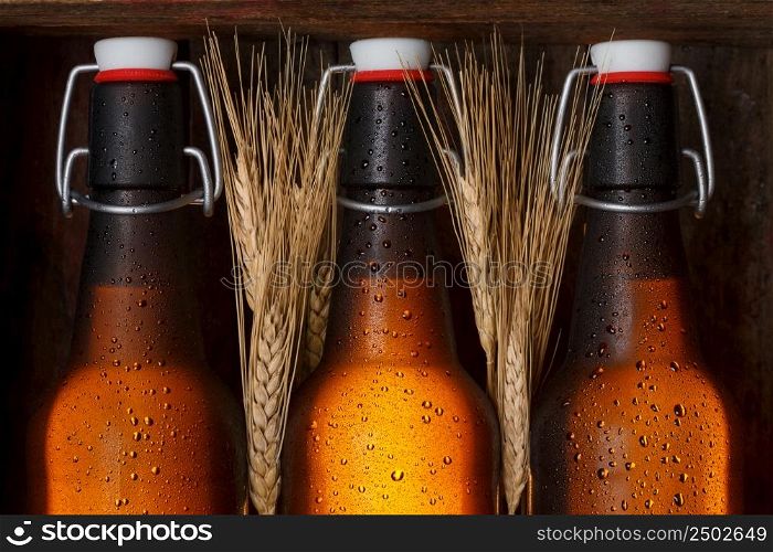 Beer bottles with wheat stems in old wooden crate still life