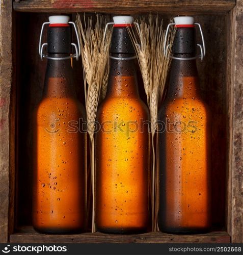 Beer bottles with wheat stems in old wooden crate still life