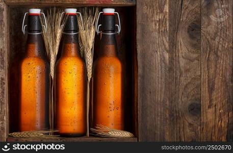 Beer bottles with wheat stems in old wooden crate still life, with copy space