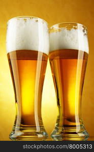 Beer close-up with froth over yellow background