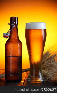 Beer glass and bottle with swing top with wheat bunch on wooden table